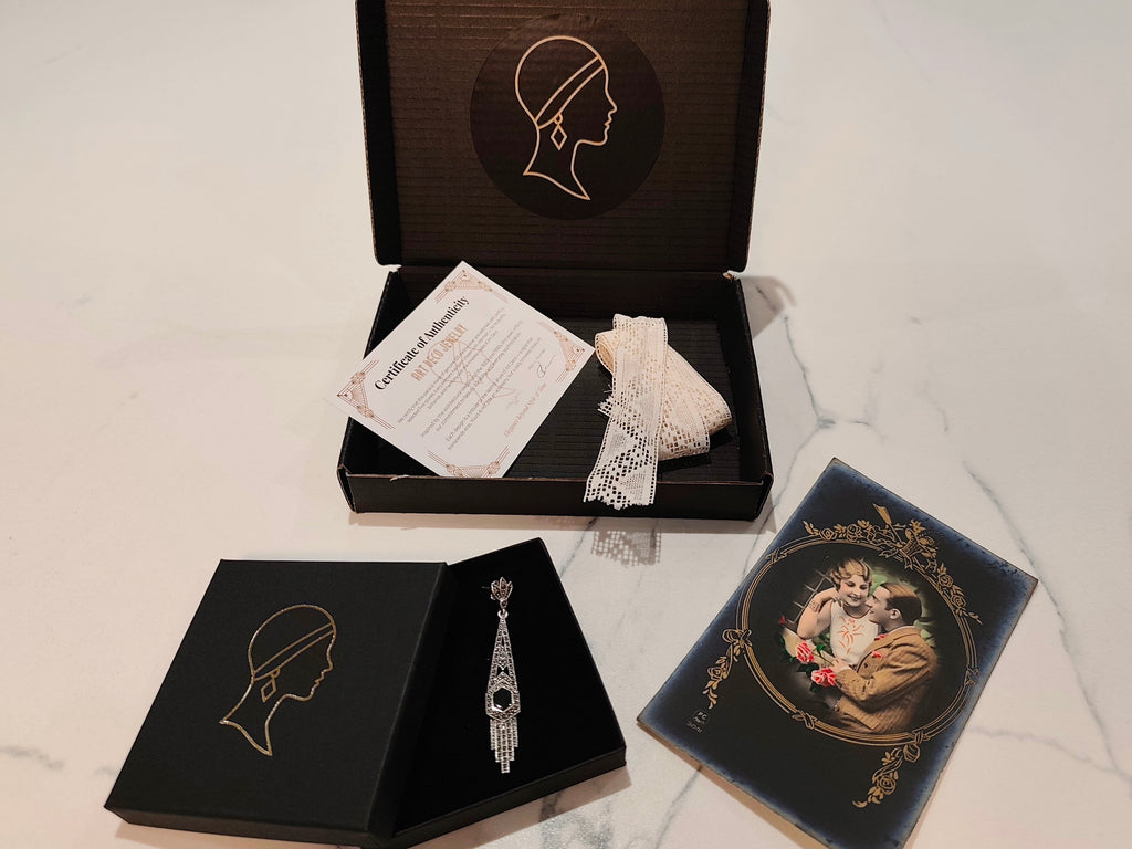 jewelry set with every order of art deco jewelry shop. black shi^^ing box with logo in gold, small box with pair of art deco silver earrings woth onyx inlay, a true 1930's postcart and an authentic lace from 1930 and a certificat of authenticity.